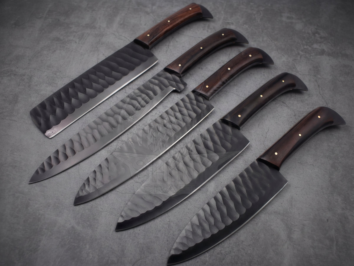 5 pieces black finish steel chef knife set with reddish brown wood handle on dark stone background