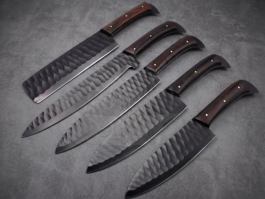 5 pieces black finish steel chef knife set with reddish brown wood handle on dark stone background