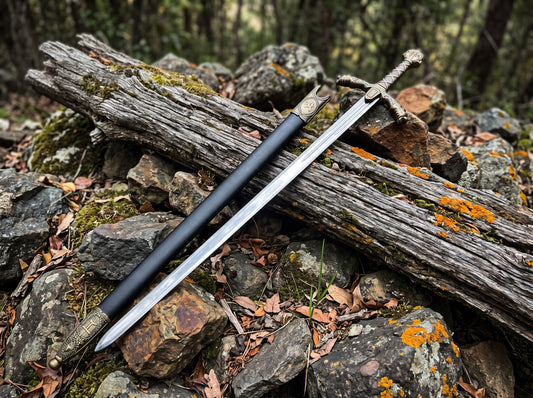 Decorative sword and black sheath with engraved chape lying side by side on a mossy log and rocks