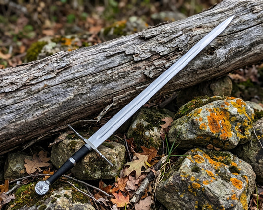 Full length decorative sword with polished grooved blade and wolf head pommel resting on rocks and autumn leaves