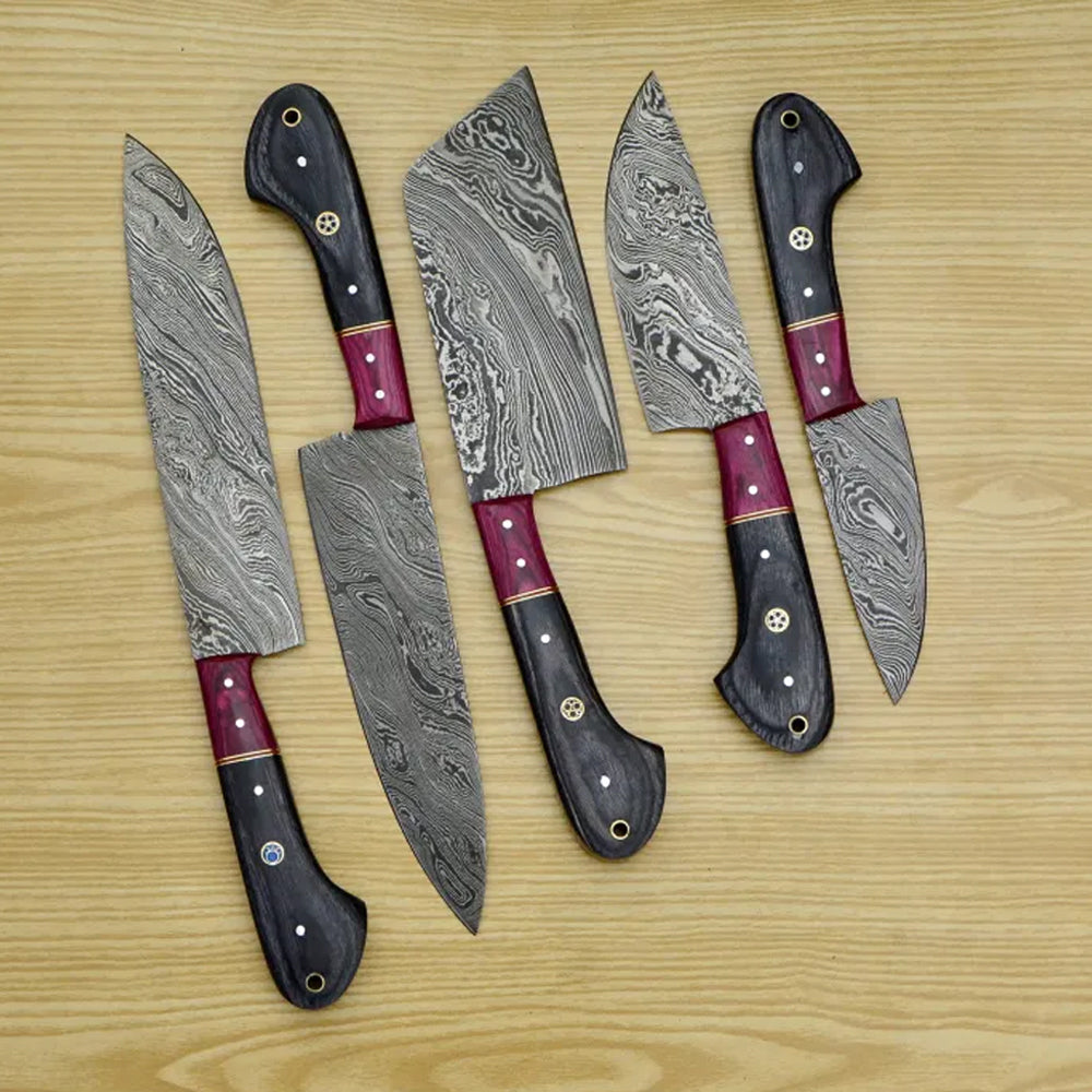 5 piece Damascus steel chef knife set with black pakka wood handles on wood table