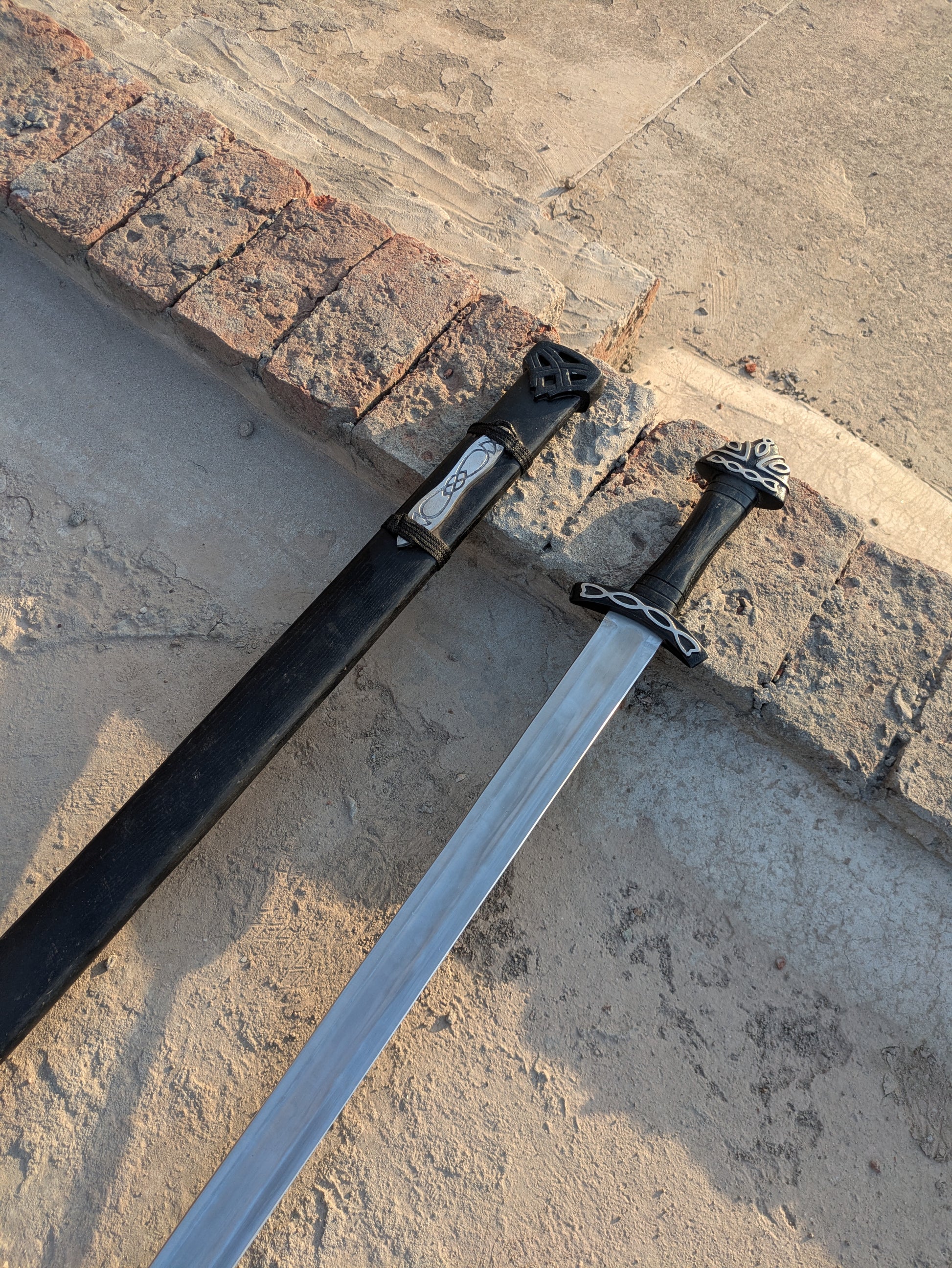 Handmade Fantasy Sword close-up showing carved pommel and crossguard on stone steps