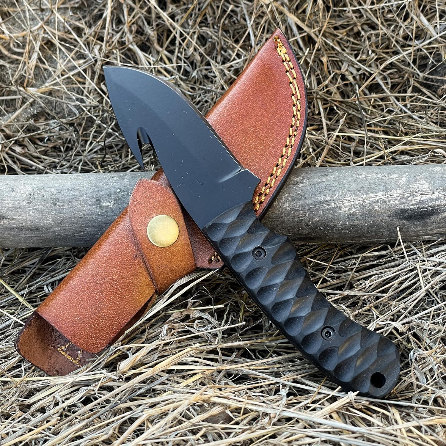 High Carbon Steel Gut Hook Skinning Knife and brown leather sheath laid outdoors on wooden piece
