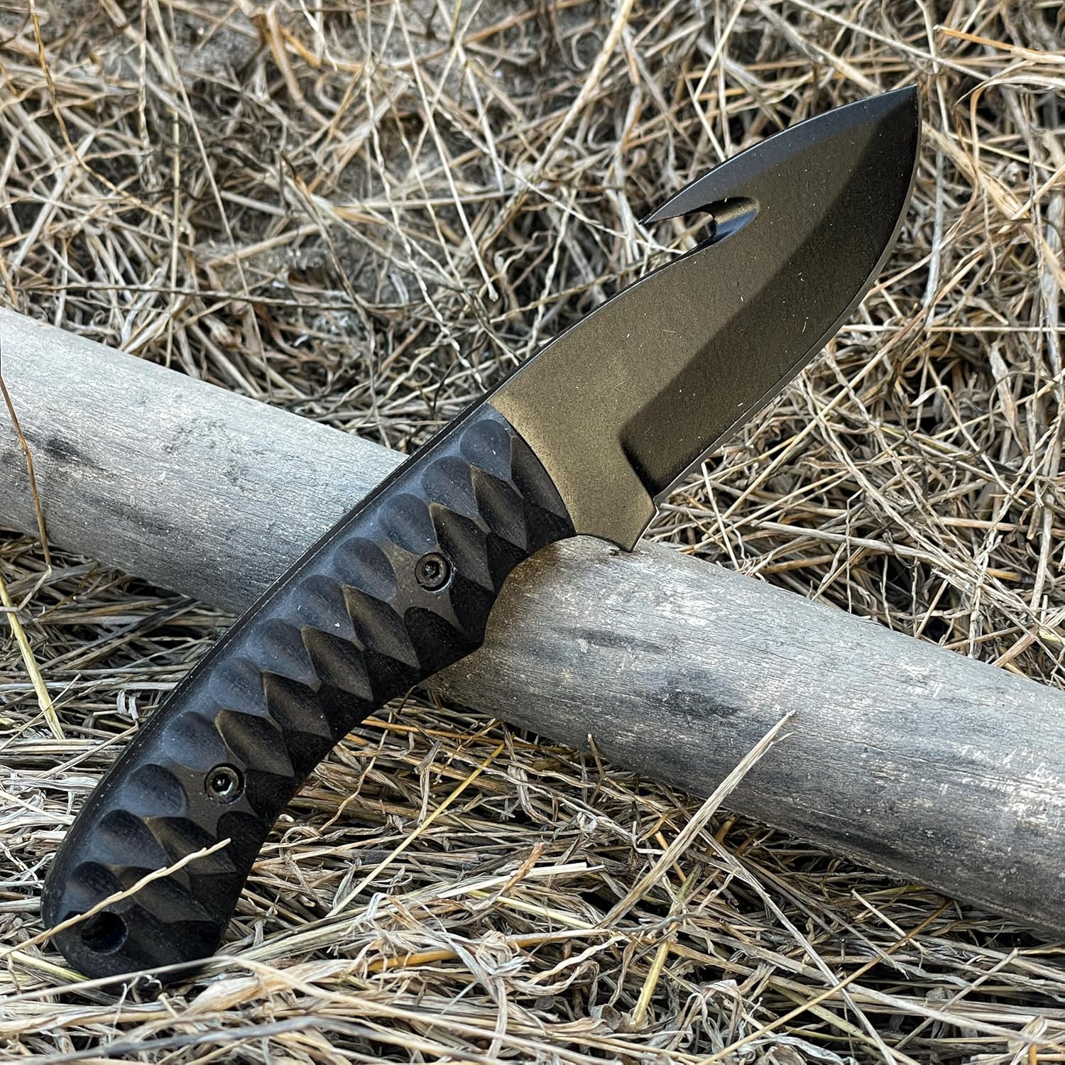 High Carbon Steel Gut Hook Skinning Knife with black blade and textured handle on wood log