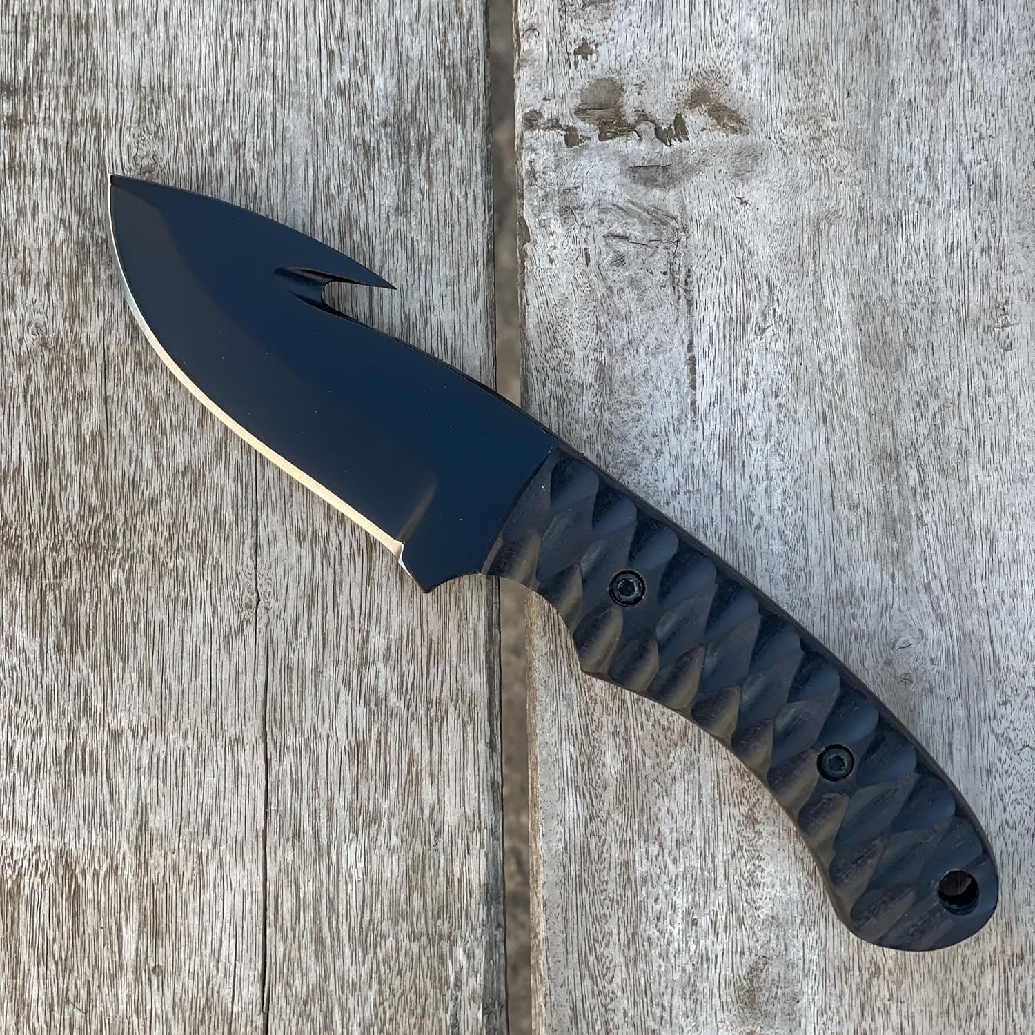 High Carbon Steel Gut Hook Skinning Knife with black blade on rustic wood plank background
