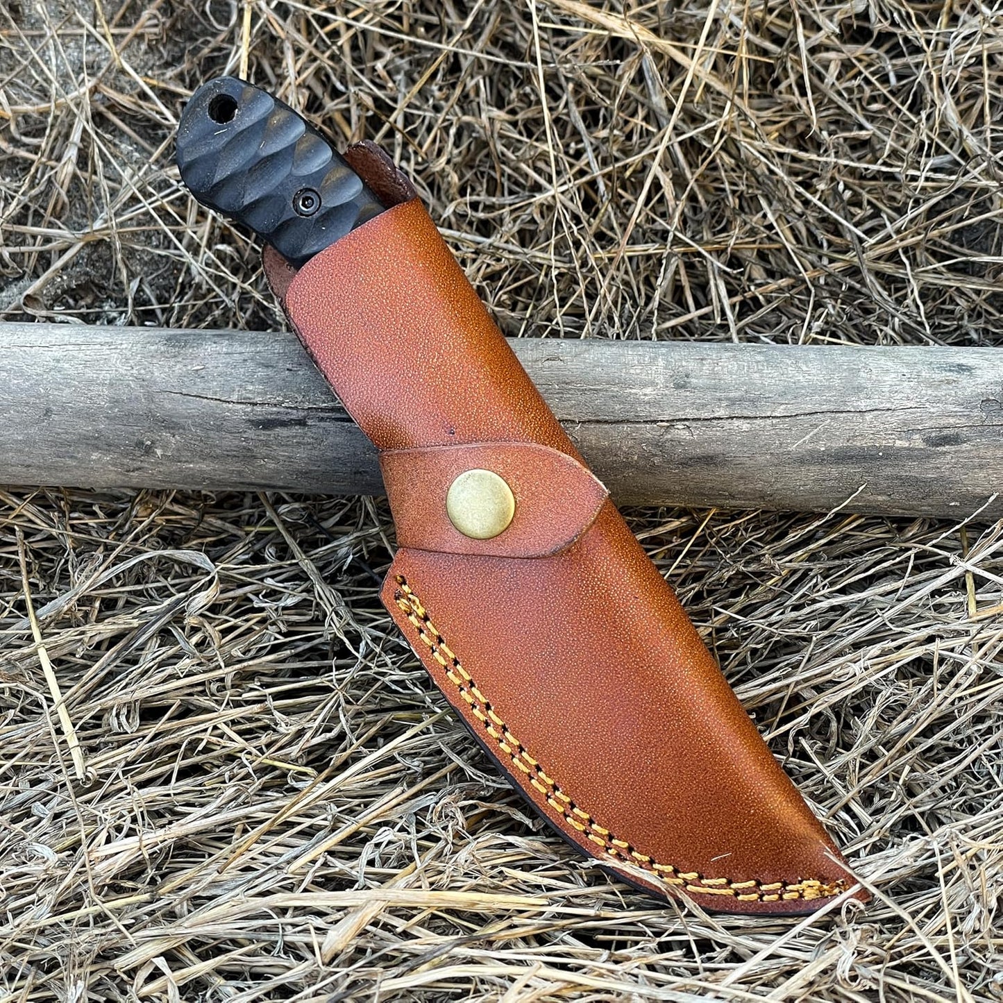 High Carbon Steel Gut Hook Skinning Knife sheathed in brown leather with snap closure outdoors