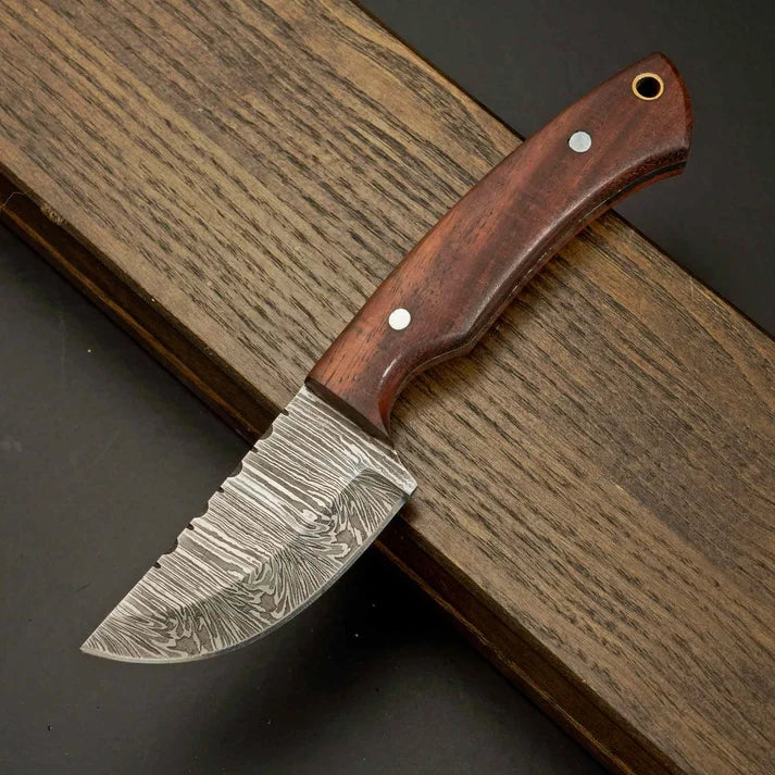 Damascus skinner knife with wooden handle displayed on wooden surface