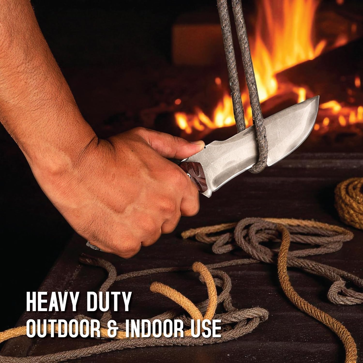 Action shot of a hand slicing thick rope with a full tang tracker knife near a warm fire. Text notes its heavy duty outdoor and indoor use.
