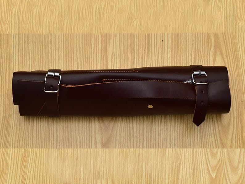 Brown leather storage roll bag with metal buckles. 