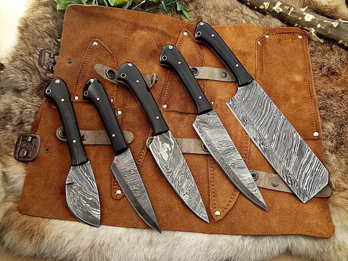 Damascus kitchen knife set of five with black horn handles on a suede roll