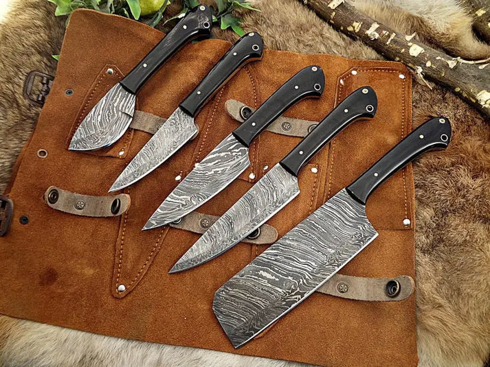Damascus knives with black horn handles fanned across an open leather roll