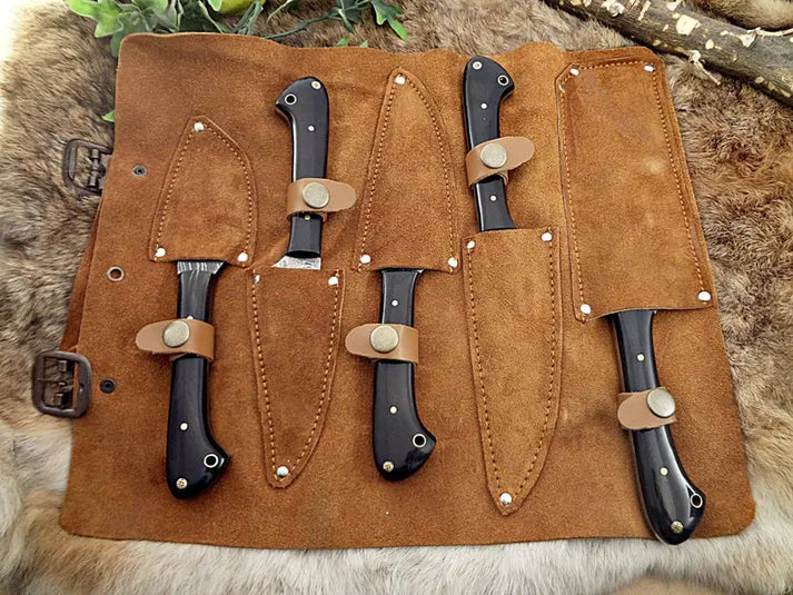 Suede leather knife roll with five black horn knives sheathed and strapped in