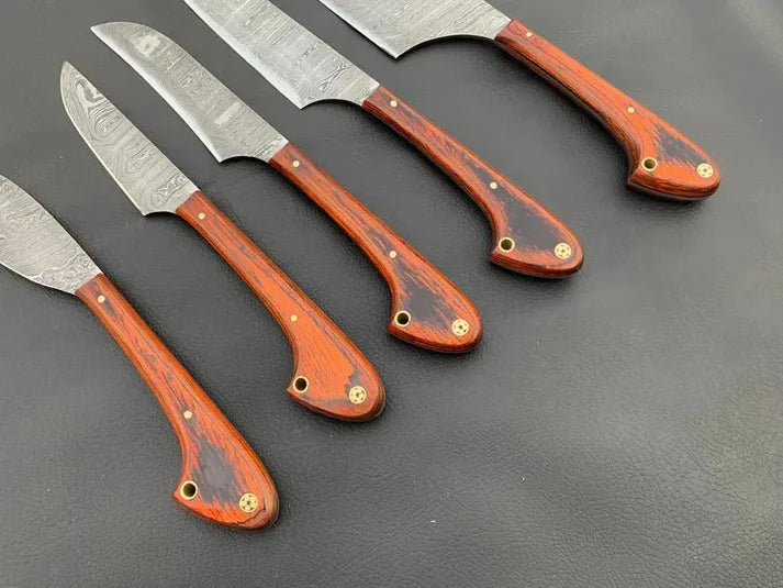 Orange pakkawood knife handles with brass mosaic pins and lanyard holes up close