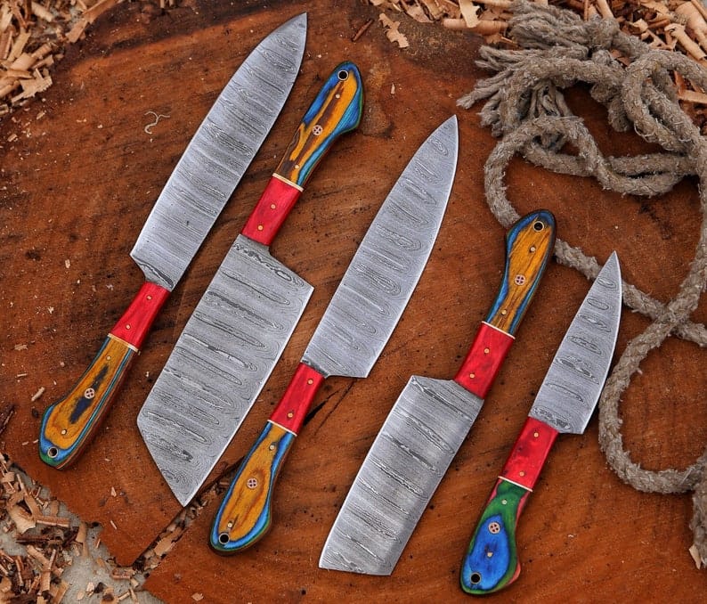 5 piece Damascus steel chef knife set with red pakka wood handles on wood stump
