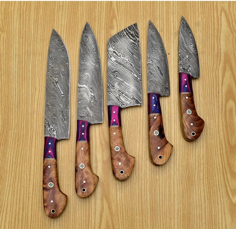 5 piece Damascus chef knife set on a wooden background. 