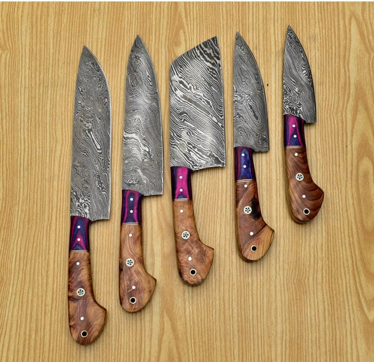 5 piece Damascus chef knife set on a wooden background. 