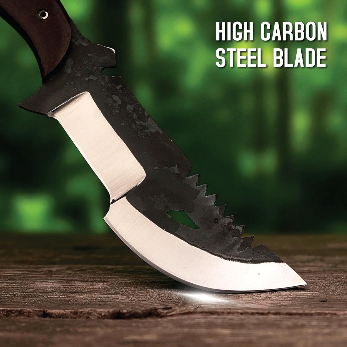 A close-up image focusing on the heavy-duty blade of a survival tracker knife, with its tip resting on a weathered wooden surface against a softly blurred green forest background. The distinctive two-toned blade features a dark, rustic, mottled upper section with saw teeth along the front spine and a teardrop-shaped cutout. This dark finish contrasts sharply with the bright, polished silver of the compound cutting edge. A bright gleam highlights the tip where it meets the wood. In the upper right corner, bo